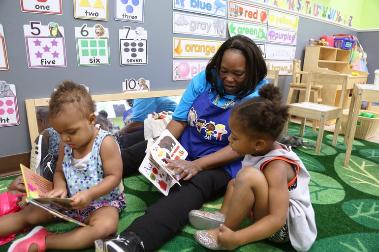 a teacher reads to two young learners